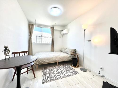 Cette petite chambre blanche comprend un lit et une table. dans l'établissement YIAN-Kamiochiai house, à Tokyo