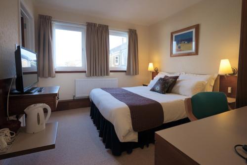 a hotel room with a bed and a flat screen tv at The Cedars Guest House in Dunoon