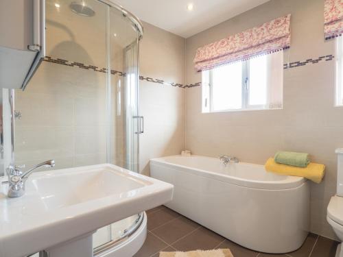 a bathroom with a tub and a sink and a toilet at High Cliff Gwbert in Towyn