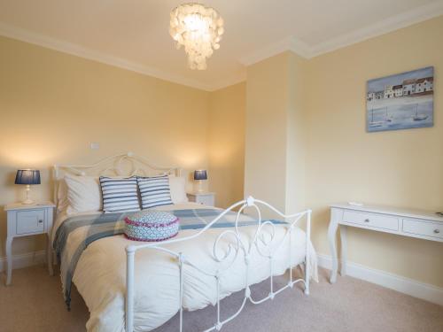 a bedroom with a white bed and a chandelier at High Cliff Gwbert in Towyn