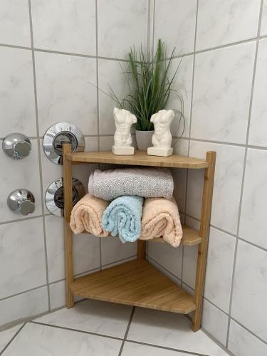 a wooden shelf in a bathroom with towels and a plant at Ferienwohnung Rosch in Konz