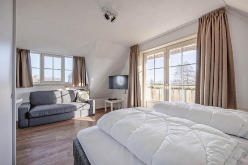 a bedroom with a bed and a couch and a window at Dutchen Waddenduyn in Den Burg