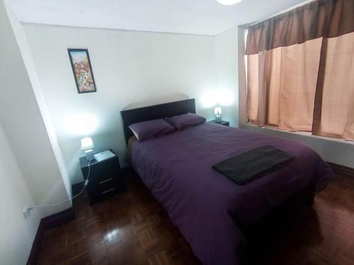 a bedroom with a purple bed and a window at Departamento amplio y lujoso - excelente ubicación in Quito