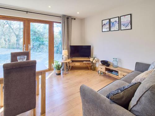 ein Wohnzimmer mit einem Sofa, einem Tisch und einem TV in der Unterkunft Host & Stay - Oak Barn in Ashford