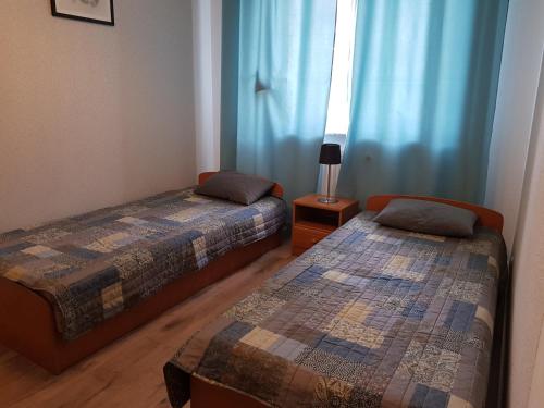 two beds in a room with blue curtains at Ustka Na Wydmie in Ustka