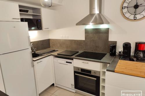 a kitchen with white appliances and a clock on the wall at Villa T3 climatisée en résidence avec piscine in Vias