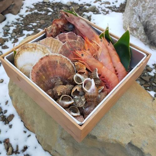 a container filled with different types of seafood on a rock at villa福座 in Furusan