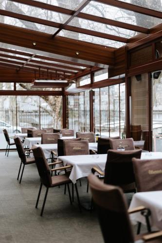 a dining room with tables and chairs and windows at Hotel Vila Vrbas in Banja Luka