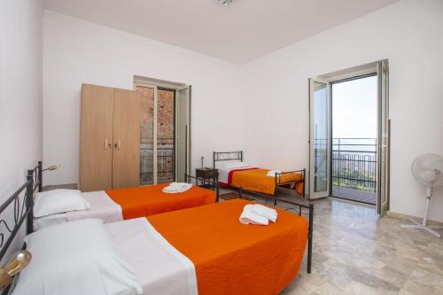 Cette chambre comprend 3 lits avec des draps orange et blancs. dans l'établissement Casa D'alunzio - appartamento 1, à San Marco dʼAlunzio