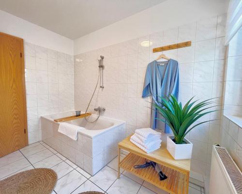 een badkamer met een bad, een douche en een plant bij TIMELESS APARTMENT: FREE PARKING + BALCONY in Wuppertal