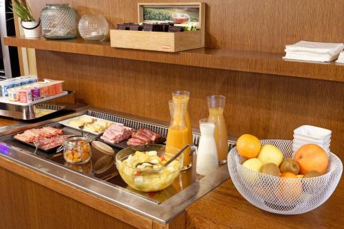 a buffet with food and a bowl of fruit and juice at Contact Hôtel de la Gare et son restaurant Côte à Côte in Autun