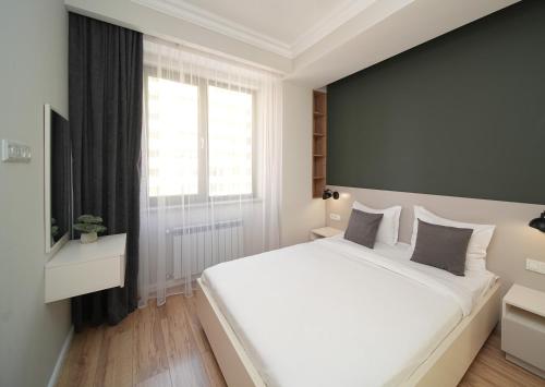 - une chambre avec un grand lit blanc et une fenêtre dans l'établissement Sweet Home Apart-Hotel, à Erevan
