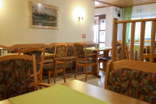 uma sala de jantar com mesas e cadeiras num restaurante em Hotel Garni KAMBEITZ em Ötigheim