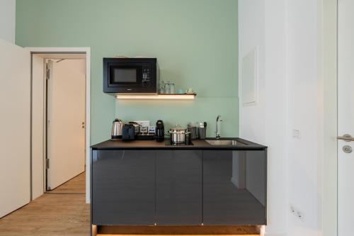 a kitchen with a black counter and a microwave at Nena Apartments Berlin Adlershof in Berlin