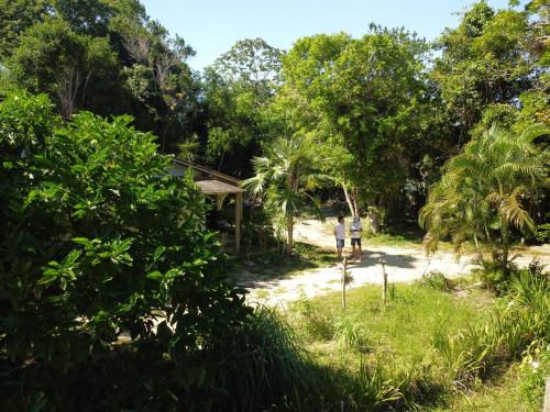 two people walking down a dirt road in a forest at Espaço Pé de Mangaba - Natureza e Simplicidade in Cumuruxatiba