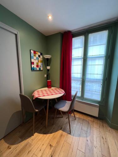 a room with a table and chairs and a window at Les Petits Apparts Versailles in Versailles