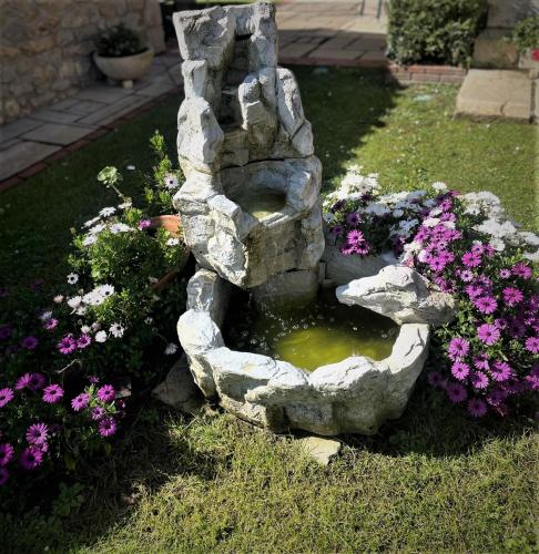 a rock fountain in a garden with flowers at Posada La Victoria in Miengo