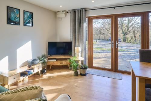 a living room with a tv and a sliding glass door at Host & Stay - Willow Barn in Aldington