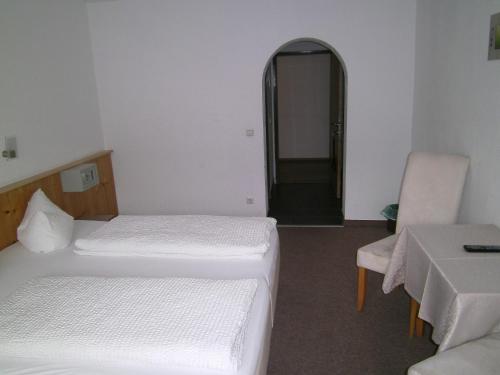 a room with two beds and a table and a chair at Gasthof Hotel Kirchenwirt in Zell am Ziller