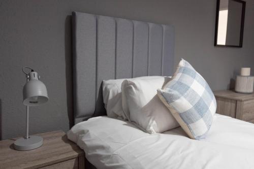 1 cama con sábanas blancas y almohada azul y blanca en Dubbie House en Leven-Fife