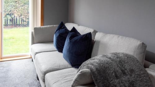 a white couch with blue pillows in a living room at Dubbie House in Leven-Fife