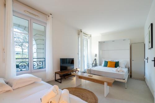 Cette chambre blanche comprend deux lits et une télévision. dans l'établissement Studio confortable : Disney & Shopping, à Serris