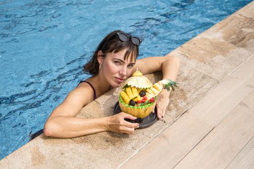 a woman in a swimming pool holding a bowl of fruit at Idou Anfa Hôtel & Spa in Casablanca