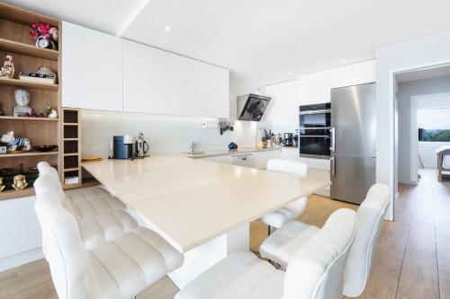 - une cuisine blanche avec une grande table blanche et des chaises blanches dans l'établissement CASSIOPEE - Face MER, à La Baule