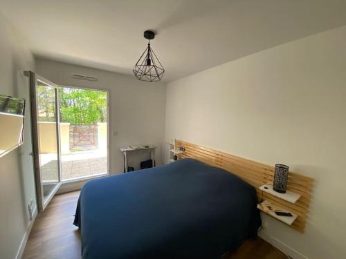 une chambre avec un lit bleu et une fenêtre dans l'établissement Bel appartement T2 sur le Bassin d'Arcachon, à Gujan-Mestras