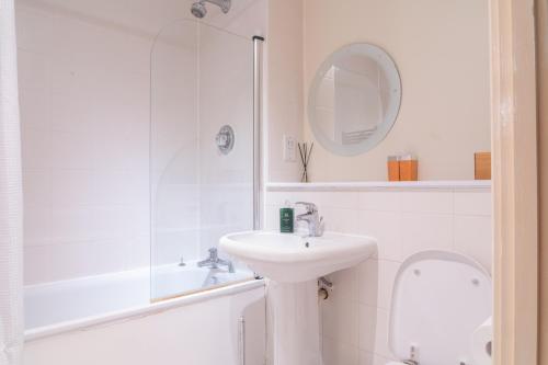 a white bathroom with a sink and a shower at Stay in our Stylish Flat! & secure building & sleeps up to 4 in Birmingham