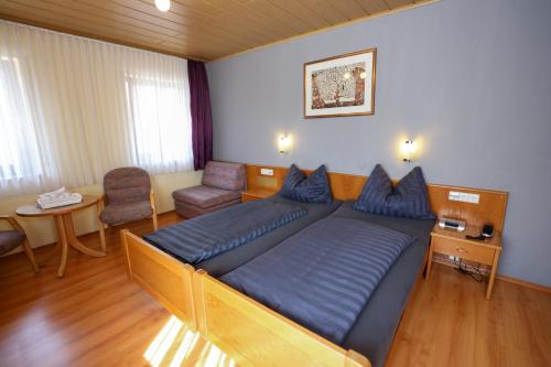 ein Schlafzimmer mit einem großen Bett und einem Stuhl in der Unterkunft Hotel Garni KAMBEITZ in Ötigheim