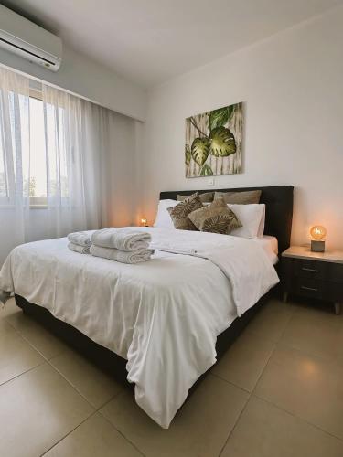 1 dormitorio con 1 cama grande con sábanas y almohadas blancas en Elysia Park Ameliya 202, en Pafos
