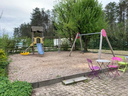 um parque infantil com cadeiras e um baloiço em Camping La Saline d'Arc et Senans em Arc-et-Senans