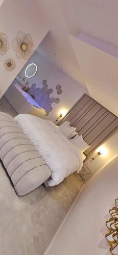 a bedroom with a large white bed and a ceiling at Douceur Dorée in Yville-sur-Seine