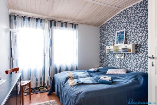 a bedroom with a blue bed with blue and white wallpaper at TurusenSaha Guesthouse in Oulu