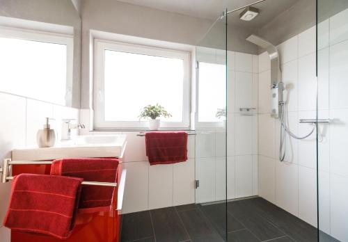 ein Badezimmer mit einem Waschbecken und einer Dusche mit roten Handtüchern in der Unterkunft Rotes Haus in Monschau