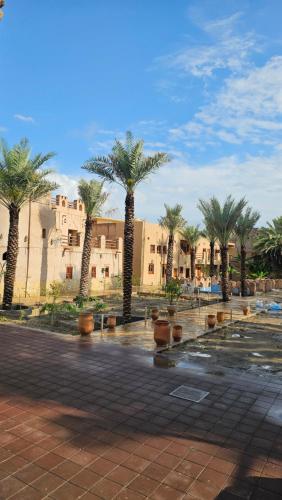 a group of palm trees in a courtyard with buildings at Aldar Inn in Nizwa