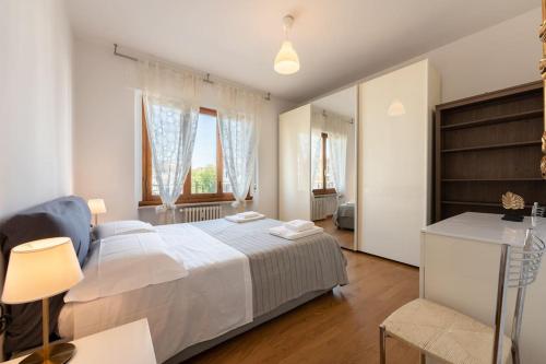 um quarto com uma grande cama branca e 2 janelas em Belfiore2 1 bedroom apt by the railways station em Florença