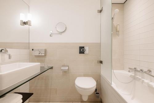 a bathroom with a toilet and a tub and a sink at Leonardo Oranje Hotel Leeuwarden in Leeuwarden