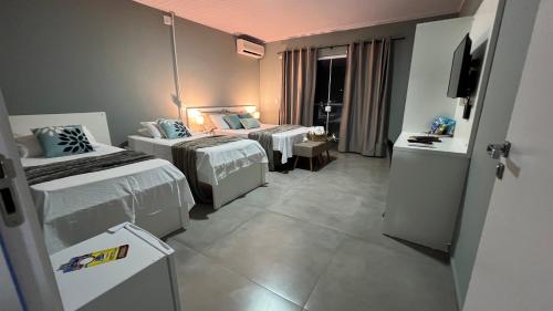 a hotel room with two beds and a television at Pousada da Bia Praia in Penha