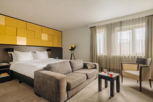 een hotelkamer met een bed en een bank bij Oranje Hotel Leeuwarden in Leeuwarden