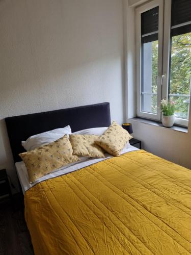 een slaapkamer met een geel bed met kussens en een raam bij City-Apartment in Krefeld, Küche, nähe Düsseldorf Messe in Krefeld