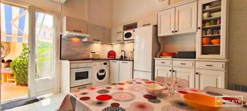 une cuisine avec une table et des placards blancs dans l'établissement Maison de vacances climatisée à 600m de la plage, à Vias
