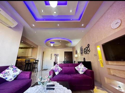 un salon avec un canapé violet et une télévision dans l'établissement Luxury apartment Madinaty families Only, à Madinaty