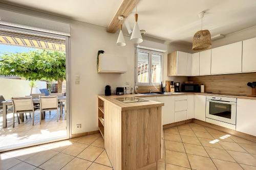 a kitchen with white cabinets and a table with chairs at Vias Plage - Villa avec piscine privé in Vias