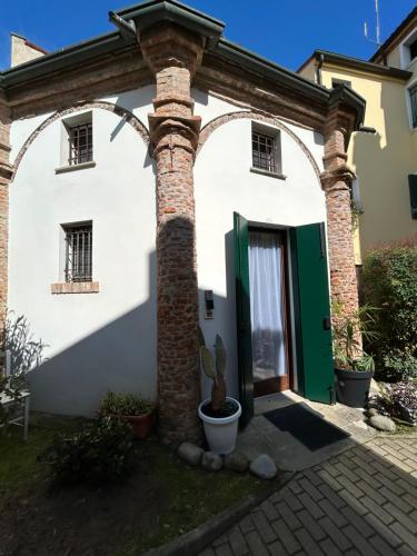 a white house with a green door and a plant at Chiesetta abside ex seminario -jvapartmentRovigo in Rovigo