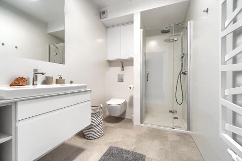 a white bathroom with a shower and a toilet at SandLand - Rogowo Pearl in Rogowo