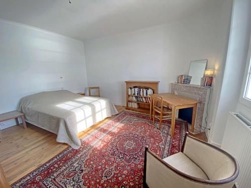 a bedroom with a bed and a chair and a rug at RÉF 407 - LARMOR PLAGE Maison de famille pleine vue mer in Larmor-Plage