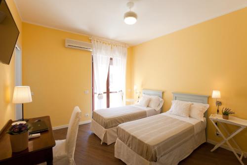 a room with two beds and a desk and a window at La Tuia e il Tasso in Cagliari