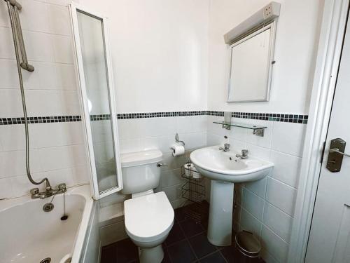a white bathroom with a toilet and a sink at 6 Knightshaven Holiday Village - Valentia Island in Knights Town